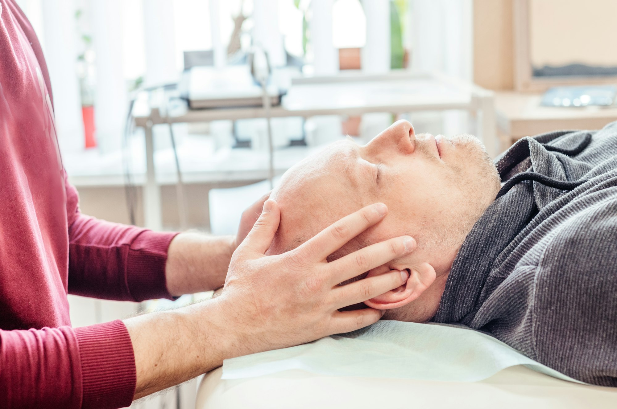 Male patient receiving cranial sacral therapy, lying on the massage table in CST practice office